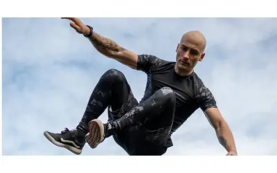 Mężczyzna w ruchu, jakby ćwiczył hiit. Co to za trening? Dynamiczne skoki i akrobacje na tle nieba.