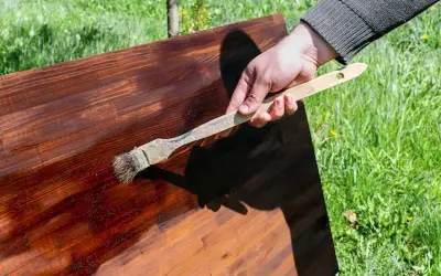 Dłoń z pędzlem nakłada olej na drewniany blat. Pytanie: czym pomalować olejowane drewno?