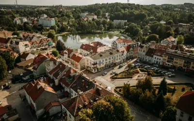 Widok z lotu ptaka na urokliwe Mrągowo. Jezioro, kolorowe kamienice i zielone drzewa tworzą malowniczy krajobraz. Odkryj mrągowo atrakcje!