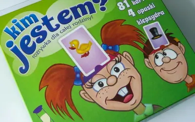Gra "Kim jestem?" to świetna zabawa dla całej rodziny! Na zielonym tle widać wesołe postacie z kartami na głowach.