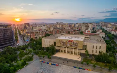 Zachód słońca nad Tirana, stolicą Albanii. Widok na plac z kolorowymi pufami i budynek z mozaiką.