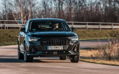 Czarny q3 audi pędzi po drodze, kierowca w okularach obserwuje trasę.