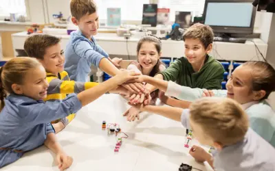 Kinder legen ihre Hände in der Mitte zusammen, ein Zeichen für Teamwork in ihrem mint kita-Projekt.