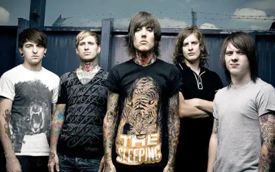 Bring Me The Horizon członkowie, z tatuażami i kolczykami, pozują przed ciemnym tłem.