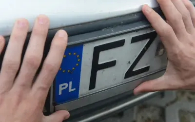 Dłonie trzymają polską tablicę rejestracyjną z literami FZ.