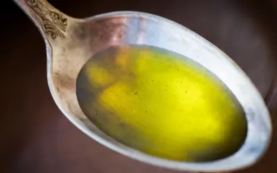 Łyżka z płynnym, żółtym olejem lnianym, który może pomóc w obniżeniu cholesterolu.