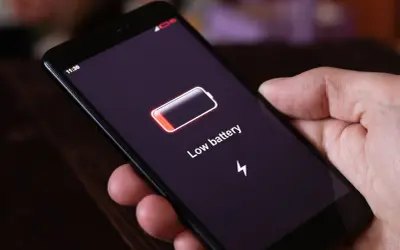 Dłoń trzyma smartfon z ikoną niskiego poziomu baterii i napisem "Low battery". Funkcja always on display pokazuje godzinę 11:30.