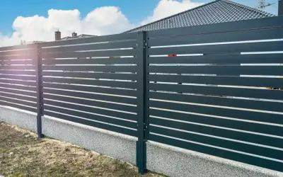 Nowoczesne ogrodzenie z poziomych paneli, osadzone na betonowym cokole. To świetne rozwiązanie, co zamiast podmurówki pod ogrodzenie, zapewniające estetykę i trwałość.