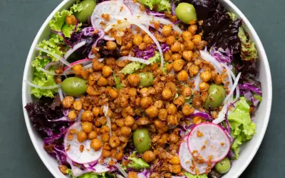 Ensalada colorida con garbanzos fritos crujientes, aceitunas verdes, lechugas variadas, rábano y cebolla morada.