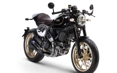Ducati Scrambler Cafe Racer negra con asiento marrón, llantas doradas y el número 54 en un círculo blanco.
