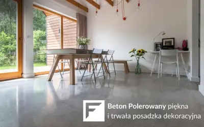 Nowoczesne wnętrze z betonem polerowanym na podłodze. Stół, krzesła, biurko i okna z widokiem na ogród.