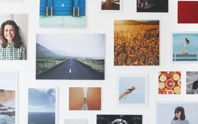 Un collage di fotografie su una parete bianca: paesaggi, ritratti, natura. Un'idea su come esporre fotografie in modo creativo.