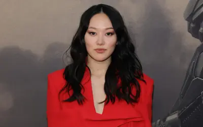 Yerin Ha, con su cabello oscuro y un elegante traje rojo, posa con confianza.
