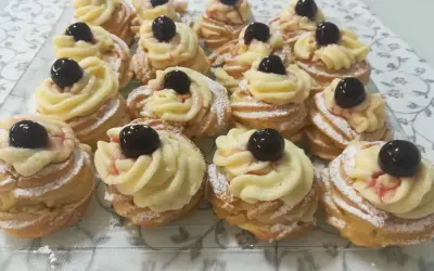 Zeppole pugliesi, dolci fritti con crema pasticcera e ciliegina, spolverati di zucchero a velo.