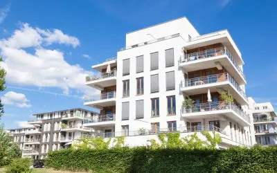 Immeubles modernes avec balcons fleuris, sous un ciel bleu. Un projet immobilier qui pourrait bénéficier de la loi Borloo pour son accessibilité.