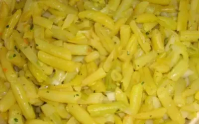 Nahaufnahme von gekochten gelben Bohnen, gewürzt mit Kräutern und Zwiebeln. Ein leckeres Gericht mit gelben Bohnen.