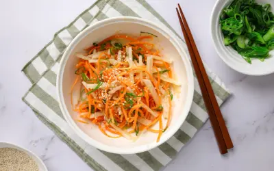 En fräsch sallad med strimlad daikon, morot och salladslök, toppad med sesamfrön. Ett enkelt daikon recept.