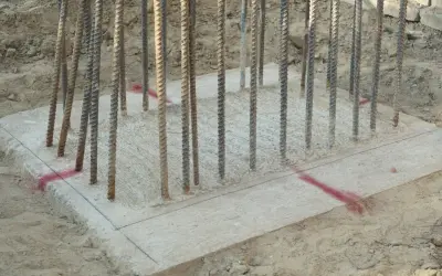 Zbrojenie fundamentów pod budowę altany ogrodowej. Betonowa płyta z wystającymi prętami, gotowa na dalsze prace.