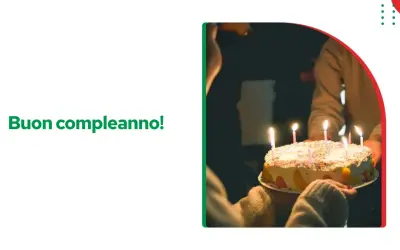 Tort urodzinowy z zapalonymi świeczkami, ktoś trzyma go w rękach. Napis "Buon compleanno!" życzy wszystkiego najlepszego sto lat po włosku.