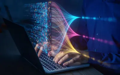Ręce na klawiaturze laptopa, wizualizacja danych w postaci kolorowych linii i kodu binarnego. Przyszłość elektrotechniki w cyfrowym świecie.