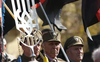 Weterani w mundurach, z symbolem Tryzub i flagami, w tym czarną z czerwonym pasem, przypominają o historii banderowców.
