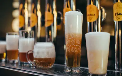 Bicchieri di birra con schiuma abbondante, tra cui una rye ipa decorata con luppoli.