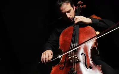 Mężczyzna gra na wiolonczeli, wydobywając z tego pięknego, choć nieco dziwnego instrumentu piękne dźwięki.