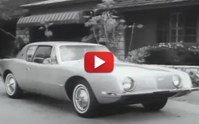 En Studebaker Avanti glider framför ett hus.