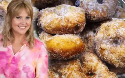 Uśmiechnięta Ewa Wachowicz prezentuje swoje pączki z ziemniakami, obficie posypane cukrem.