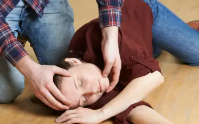 Osoba w pozycji bocznej bezpiecznej, z ręką pod głową, na podłodze.