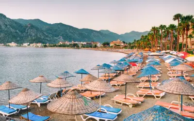 Plaża w Marmaris z rzędami leżaków i parasoli, idealne miejsce na relaks. W tle góry i hotele.