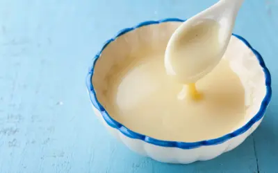 Cuchara con leche evaporada, un ingrediente cremoso y dulce, ideal para postres.
