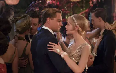 Para Gatsby'ego, taniec z Daisy to chwila magii. Ona w błyszczącej sukni, on w eleganckim garniturze, otoczeni gośćmi na przyjęciu.