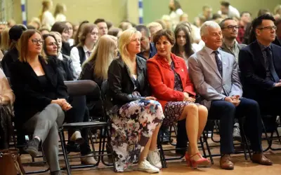 Uczestnicy siedzą na krzesłach, wśród nich widać osoby, które mogą być na radzie pedagogicznej.