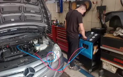Mechanik wykonuje ozonowanie klimatyzacji w samochodzie Mercedes. Urządzenie do ozonowania podłączone jest do układu.