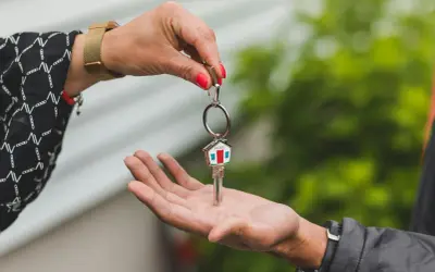 Una mano entrega una llave con un llavero de casa, simbolizando la permuta de viviendas entre particulares.