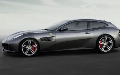 Szary Ferrari FF, sportowe kombi z charakterystycznymi wlotami powietrza i czerwonymi zaciskami hamulcowymi, prezentuje się na tle mglistego nieba.