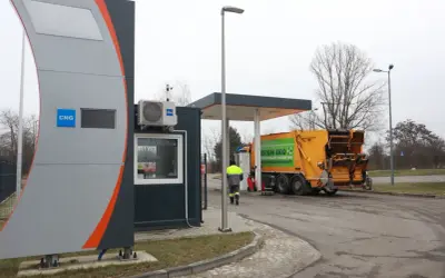 Stacja paliw z oznaczeniem CNG, gdzie można tankować gaz. Obok żółta śmieciarka z napisem "System Eko".