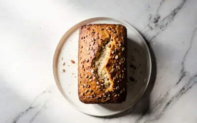 Chleb migdałowy bez glutenu z ziarnami na talerzu na marmurowym tle.