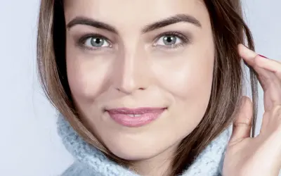 Visage de femme au regard intense, mettant en valeur ses sourcils parfaits. Elle porte un pull bleu ciel.