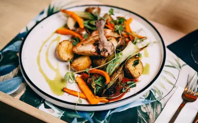 Pyszne danie z kurczaka z ziemniaczkami i marchewką, ozdobione ziołami. Idealna pozycja z **Fischgarten menu**.