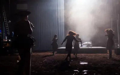 Scena teatralna z kobietami w ruchu, w tle łóżko. Może to być scena z życia Johna Proctora.