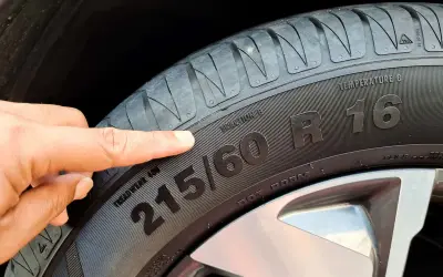 Palec wskazuje na oznaczenie opon 215/60 R16. Informacja ta jest kluczowa przy zakupie nowych opon.
