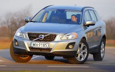 Srebrny Volvo XC60 z kierowcą na drodze. Sprawdź aktualną volvo xc60 cena i oferty.