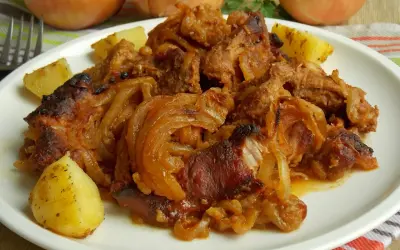 Karkówka w zupie cebulowej, duszona z cebulą i ziemniakami, podana na białym talerzu.