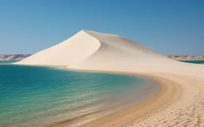 La majestueuse dune blanche de Dakhla rencontre les eaux turquoise d'un lagon paisible, sous un ciel d'un bleu éclatant.