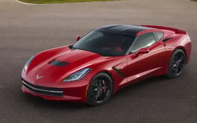 Czerwony Chevrolet Corvette Stingray z czarnym dachem na torze wyścigowym.