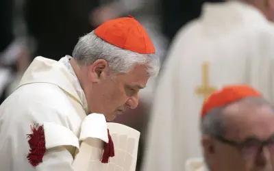 Dwóch kardynałów polskich w czerwonych biretach i białych szatach. Jeden pochyla się nad dokumentem.