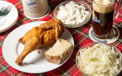 Knusprige Henne Berlin mit Brot, Krautsalat und einem Bierkrug.
