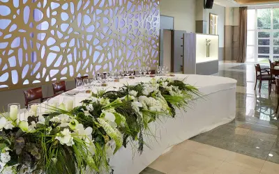 Elegante mesa presidencial boda con arreglos florales blancos y verdes, velas y copas.